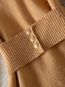 Elegant women's knit sweater featuring golden crest buttons and ribbed waist detail