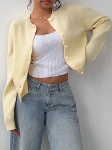 Women's pale yellow knit cardigan with white buttons and light blue straight jeans
