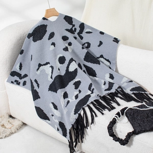 Detail of grey leopard print knit poncho featuring delicate black fringe trim and soft texture