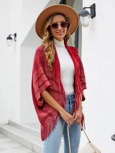 Détail d'un châle en tricot rouge avec de longues franges et un tissu doux rayé