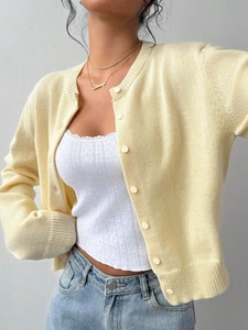 Detail of light yellow knit cardigan with ribbed cuffs and monochrome button closure