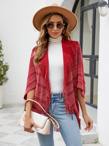 Détail du châle en tricot rayé rouge avec de longues franges sur un pull blanc et un jean