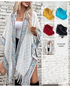 Close-up of bohemian knit hooded poncho featuring hollow-out patterns and fringe hem details