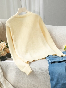 Close-up of cream yellow knit sweater featuring ribbed neck and soft knit texture