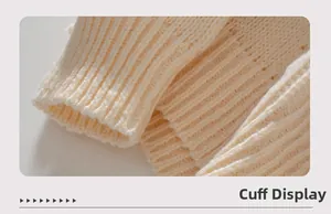 Detailed close-up of the ribbed cuff on a cream-white knit Christmas sweater
