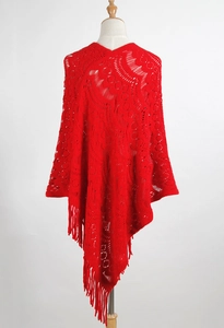 Detailed view of red crochet knit poncho featuring hollow-out patterns and tassel fringe
