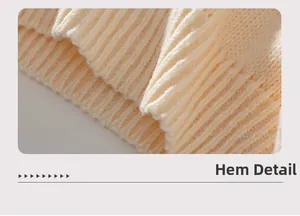 Detail of the ribbed knit hem on a cream Christmas sweater with high texture focus