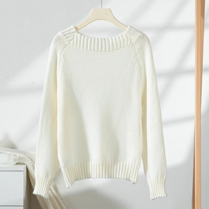 Detail of the white knitted sweater showing ribbed cuffs and soft fabric texture in natural light
