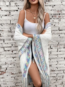 Detail view of ethnic knit poncho showing colorful bohemian trim and long fringe tassels