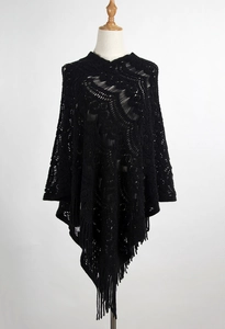 Detail of black crochet hollow knit poncho featuring bohemian fringe and intricate patterns