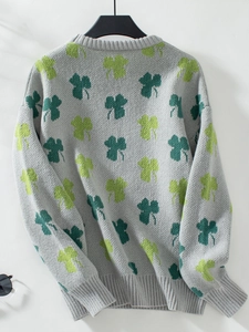 Gros plan sur le tissu en maille jacquard gris à motifs trèfles verts et finitions côtelées