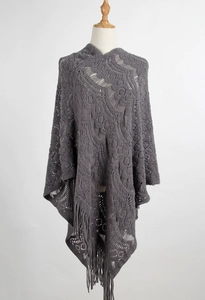 Detailed close-up of grey crochet knit poncho featuring hollow patterns and fringe trim