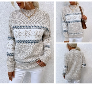 Detail of soft beige knit sweater featuring blue snowflake patterns and a high neck design