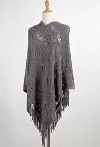 Detail of grey hollow-out knit shawl featuring intricate jacquard patterns and long fringes