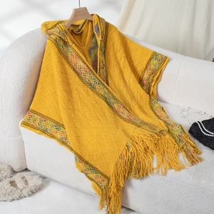 Detailed close-up of yellow knit shawl with colorful geometric patterns and long fringe