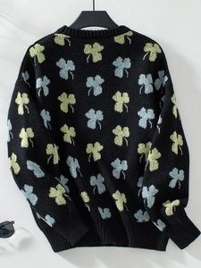 Détail du motif jacquard trèfle sur pull en maille noir avec poignets côtelés