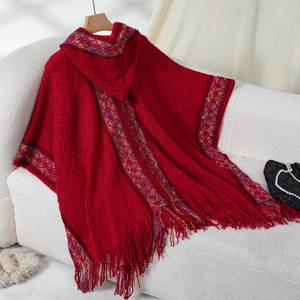 Close-up of red knit hooded poncho with diamond patterns, ethnic patterns and tassels
