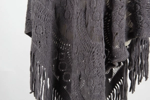 Detailed view of dark grey crochet knit shawl with openwork patterns and fringe tassels