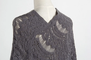 Detail of dark gray hollow crochet knit poncho with fringe and textured boucle yarn