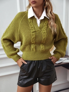 Detail eines grünen Zopfstrickpullovers mit weißem Hemdkragen und tiefem V-Ausschnitt