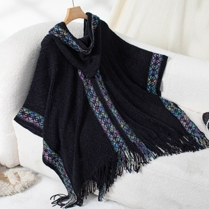 Close-up of black knit poncho with colorful ethnic trim and long fringe detail