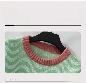 Detail of pink ribbed crew neck and green chevron wave pattern on knit sweater