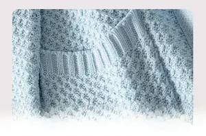 Detailed macro view of light blue waffle knit texture and ribbed pocket edge of the cardigan