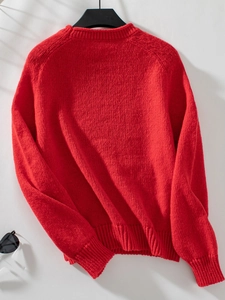 Detail of red crewneck sweater featuring ribbed cuffs and thick knit texture for winter
