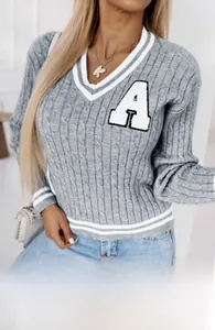 Close-up of gray cable knit sweater featuring V-neck white stripes and letter A patch