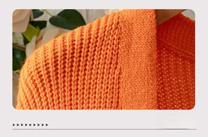 Close-up of bright orange chunky knit fabric with textured honeycomb and rib patterns