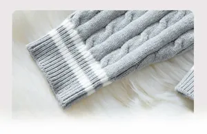 Macro shot of grey cable knit sweater cuff with double white stripes and ribbed texture