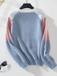 Detail of color-block cable knit sweater showing blue pink and white stitch texture