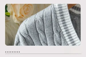 Detail of grey cable knit fabric with ribbed v-neckline and decorative flowers
