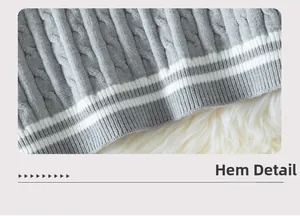 Close-up of gray knit sweater hem with ribbed texture and dual white stripes detail
