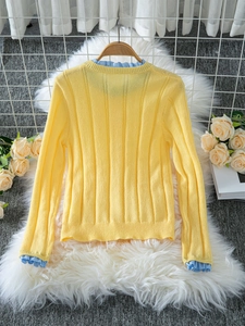 Yellow long sleeve knit cardigan with blue plaid ruffle trim on white fur rug