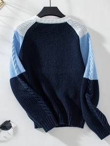 Detail of color-block cable knit sweater showing navy, light blue, and white ribbed sleeve