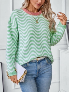 Detailed knit texture of a green and white chevron wave pattern sweater with pink crew-neck