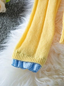 Close-up of yellow ribbed knit cuffs with blue gingham ruffled hem detail on a cardigan