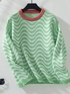 Detail view of chevron wave stripes and red ribbed neckline on the green knit sweater