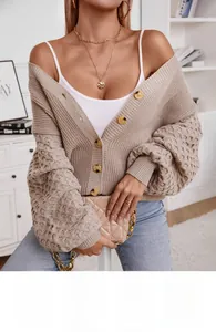 Detail of chunky beige knit cardigan featuring honeycomb textured sleeves and large buttons