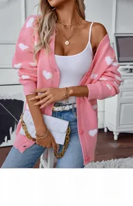 Gros plan d'un cardigan en maille rose avec motifs de cœurs blancs et boutons simples