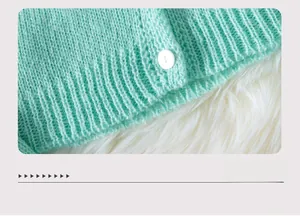 Detail of mint green knit cardigan hem with ribbed texture and white pearl button