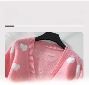 Gros plan du cardigan en tricot rose avec broderie cœur blanc et texture col en V