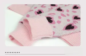 Close-up of ribbed cuffs on pink and white knit sweater with black leopard heart pattern