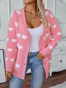 Gilet en maille rose avec motif cœur blanc et boutons dans un cadre intérieur confortable