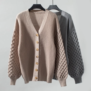 Detail of chunky knit cardigan featuring V-neckline and textured honeycomb sleeves