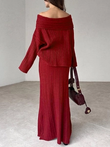 Detail of red two-piece knit set showing ribbed texture on off-shoulder top and maxi skirt