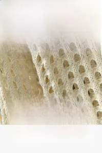 Dettaglio del tessuto in maglia traforata crema con trama morbida e traspirante