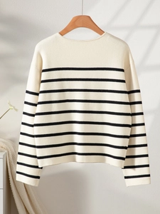 Close-up of black and white striped knit cardigan texture on a wooden hanger