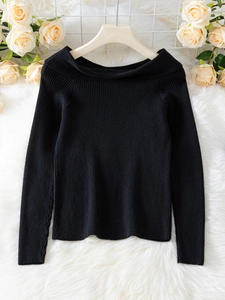 Detail of black off-the-shoulder sweater featuring fine ribbed texture and folded neckline